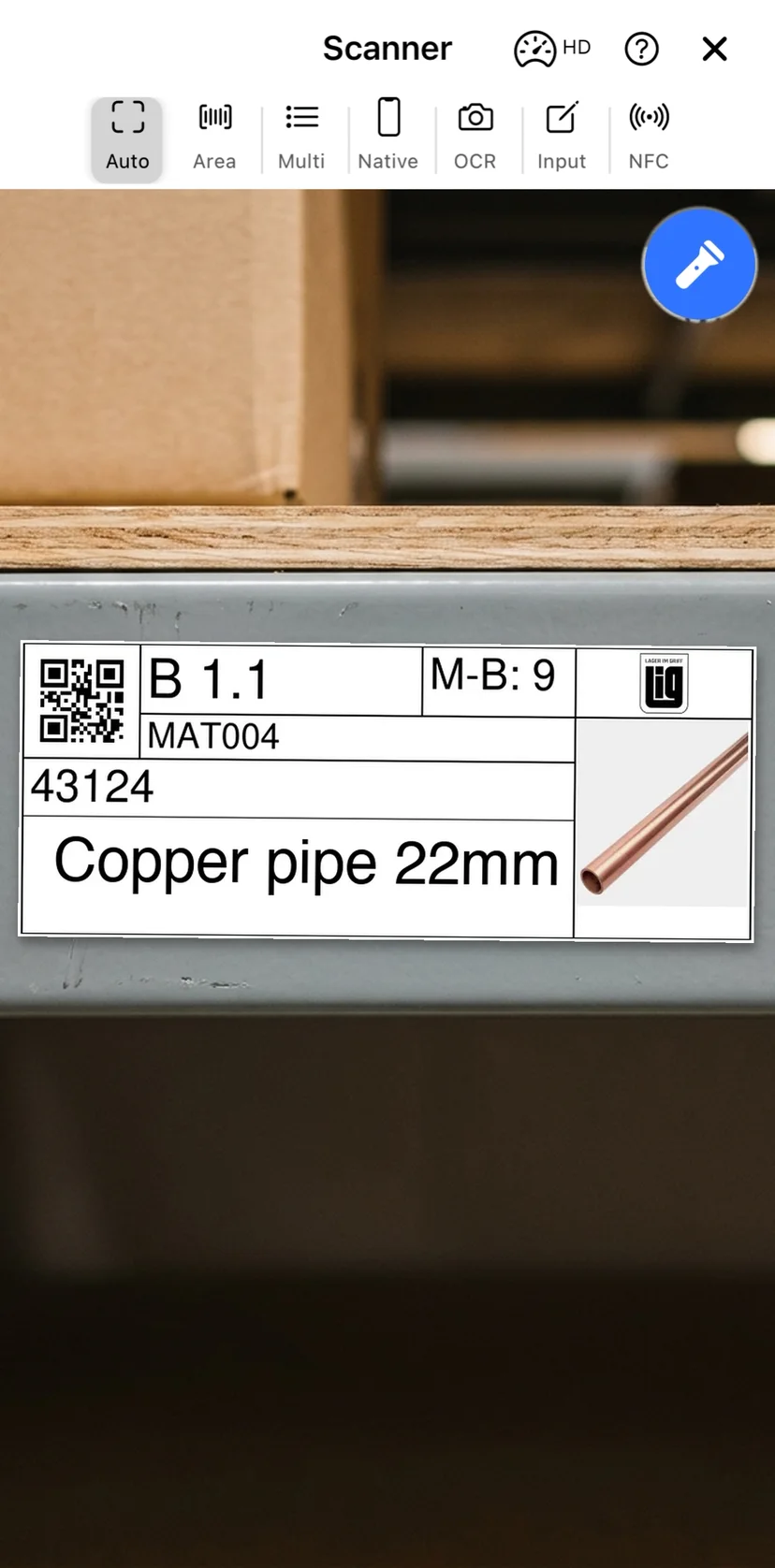 The mobile app scanner pointed at a printed QR label on a warehouse shelf