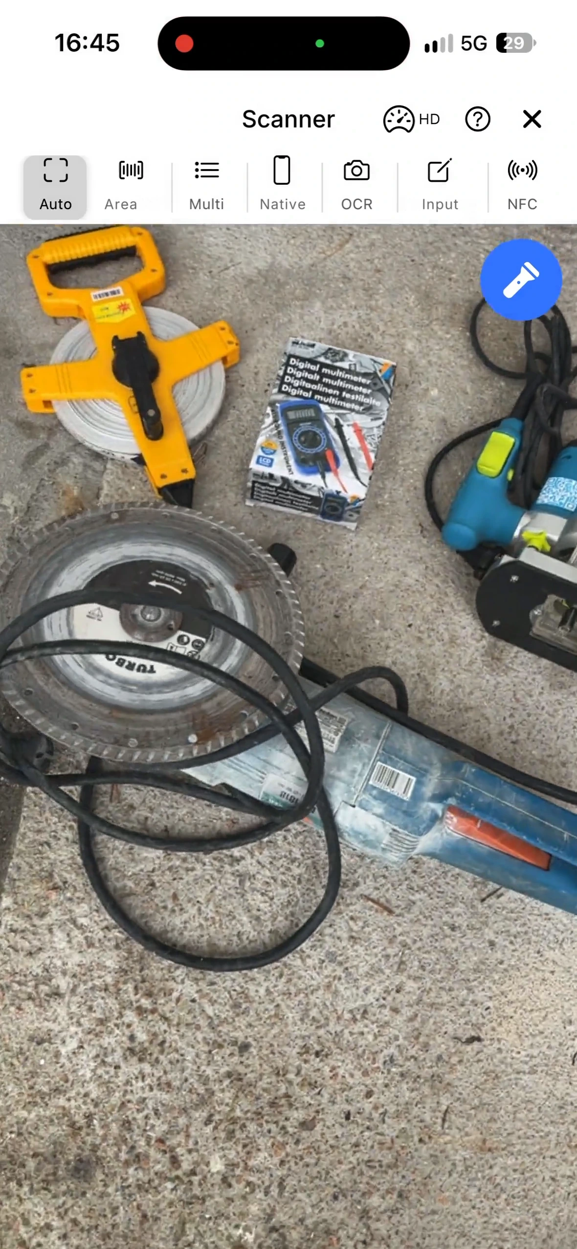 The scanner in the mobile app reads the barcode on an angle grinder lying among other tools